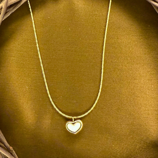 Gold necklace with a heart-shaped pendant on a brown background